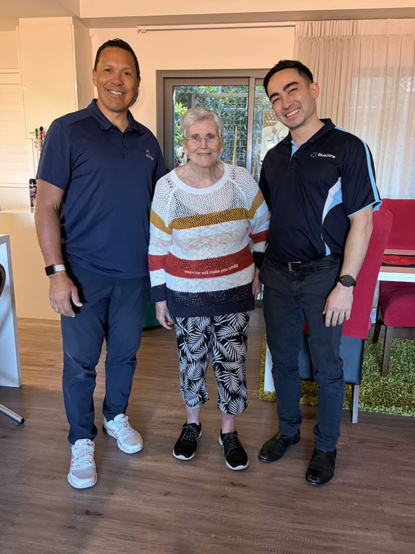 A BlueZone clients stands smiling with Chris Chan and a care worker